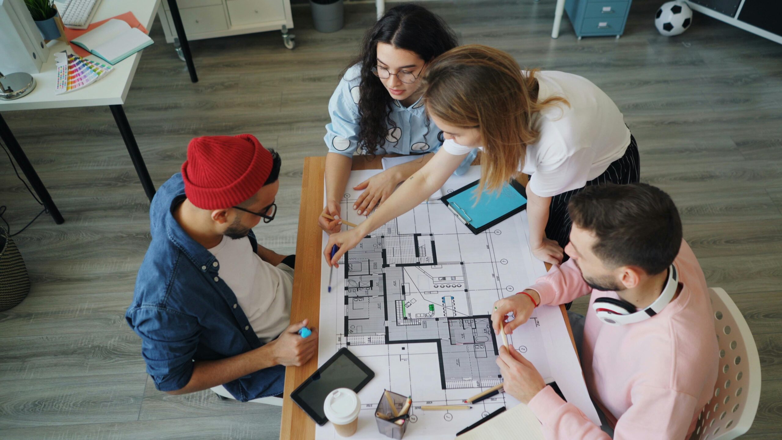 Young creative professionals discussing an architectural blueprint in a modern office setting.